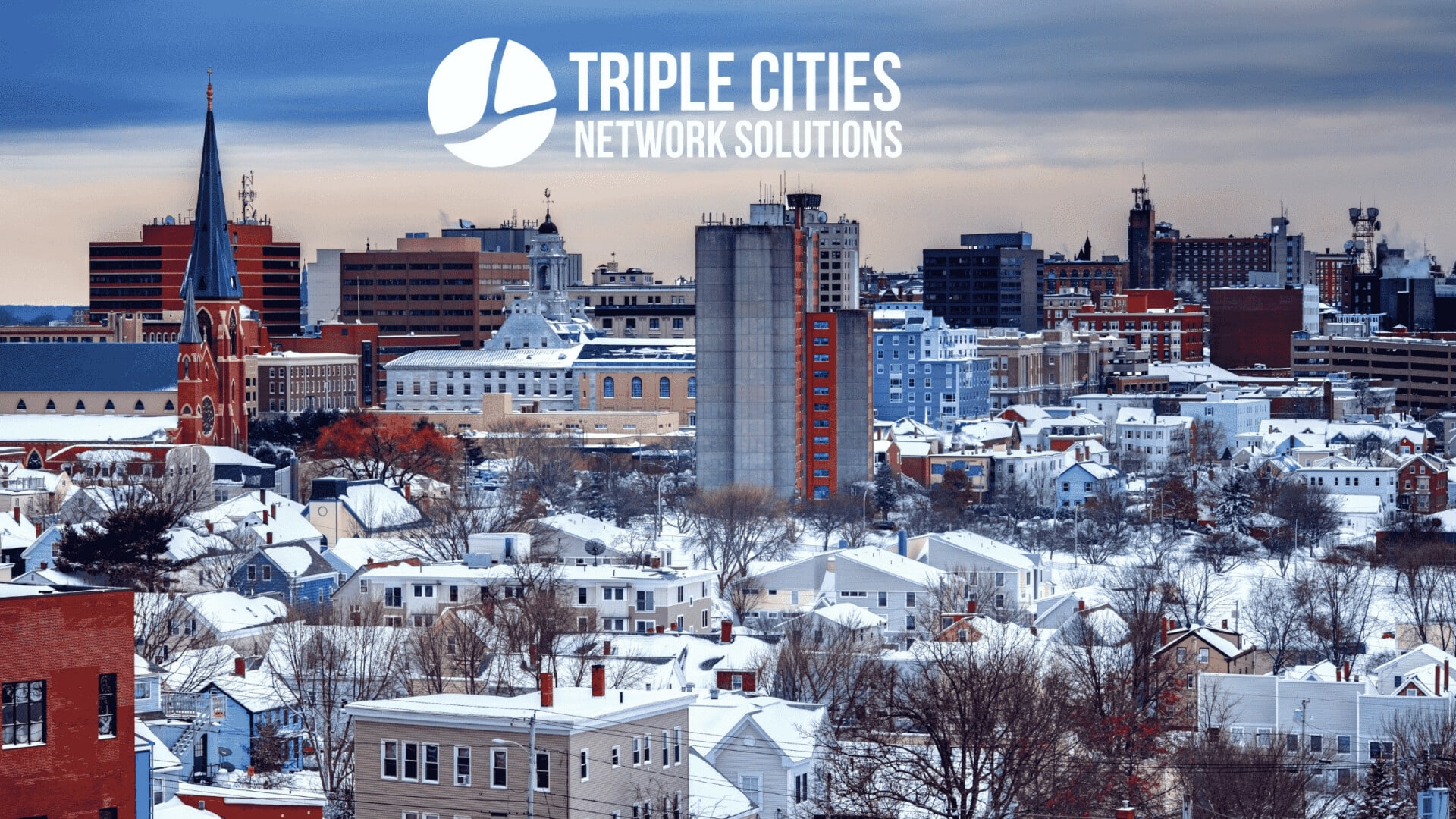 Cityscape blanketed in snow with a skyline of various buildings, including New York IT's iconic office tower. A logo in the sky reads "Triple Cities Network Solutions." Secure your digital world with reliable backup solutions amidst the urban chill, supported by New York IT’s advanced technological innovations.